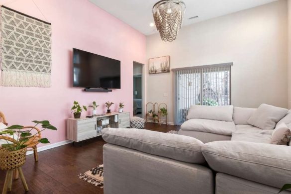 Un salon bohème avec un mur rose poudré, un canapé gris clair et un lustre en perles pour choisir les couleurs idéales d'une ambiance douce et chaleureuse.