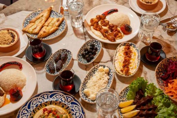 Une table garnie de nombreux plats orientaux colorés, dattes, olives, pain et kebab, illustrant les riches habitudes alimentaires du Moyen-Orient.