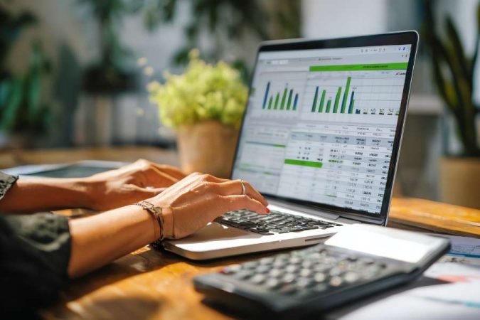 Une comptable utilise un ordinateur portable affichant des graphiques financiers et des tableaux de données comptables.