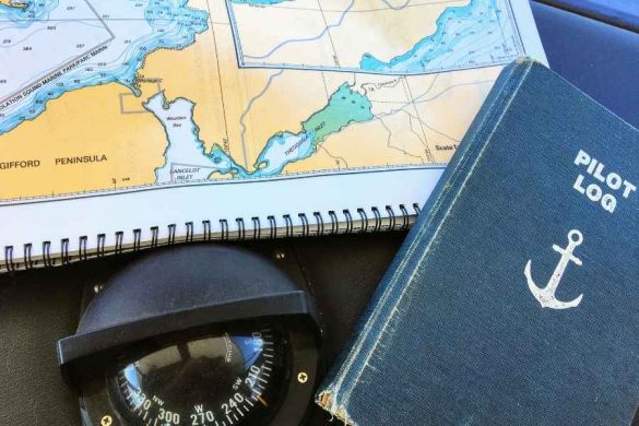Un carnet de type journal de bord de voyage posé sur une carte marine avec une boussole.